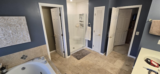 bathroom featuring a closet, a stall shower, baseboards, and a garden tub