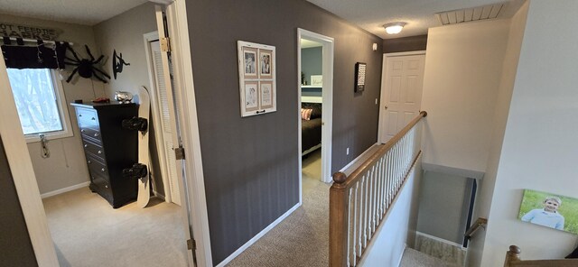 corridor with an upstairs landing, baseboards, and carpet floors