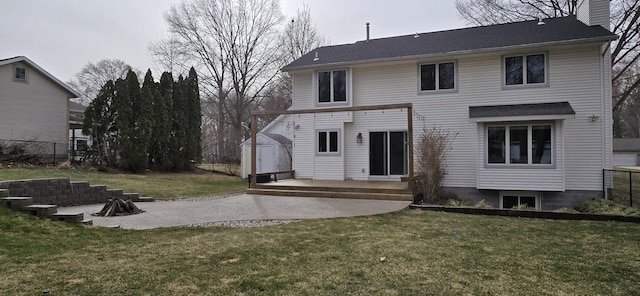 rear view of house with a yard, a deck, a chimney, and fence