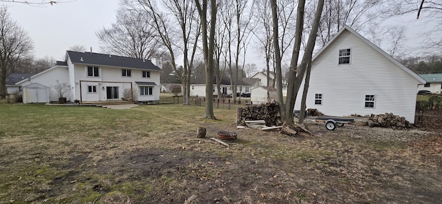 back of house featuring a yard, an outbuilding, a storage shed, and fence