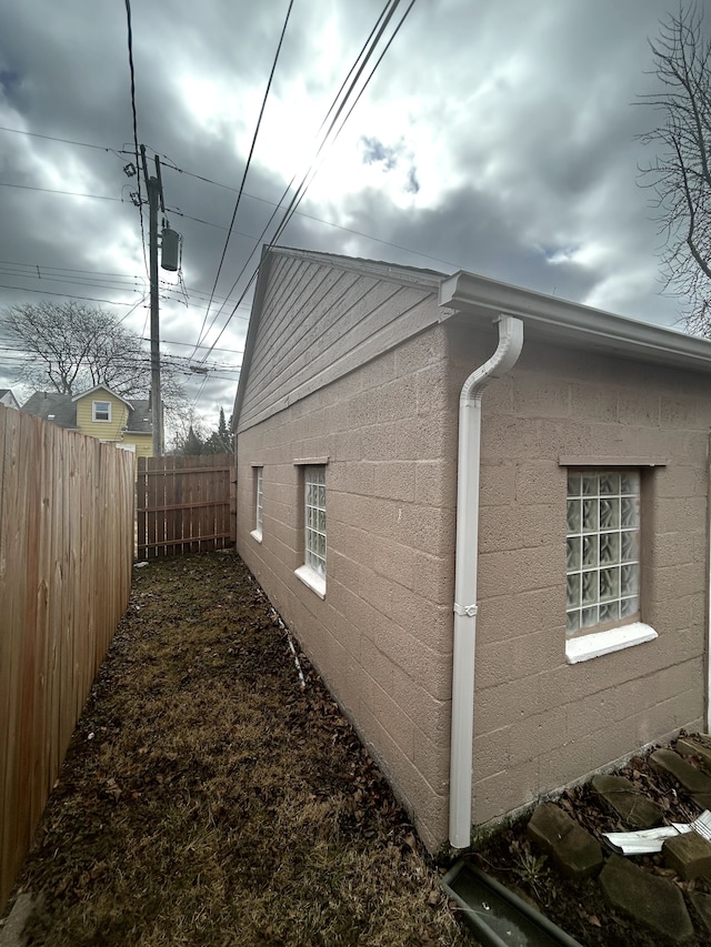 view of side of home featuring concrete block siding and a fenced backyard