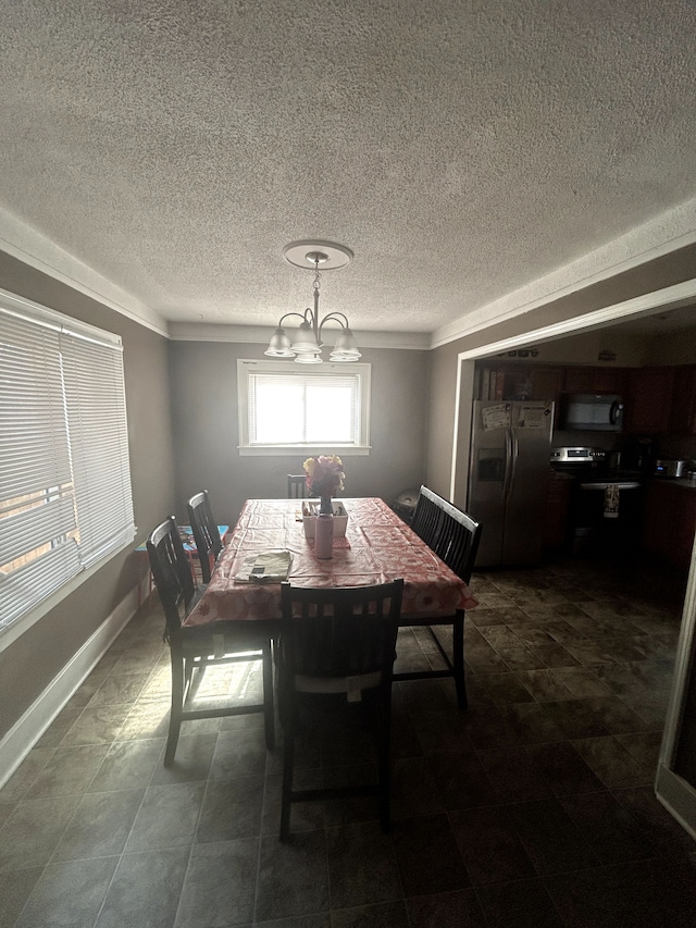 dining room featuring a chandelier, a textured ceiling, and baseboards