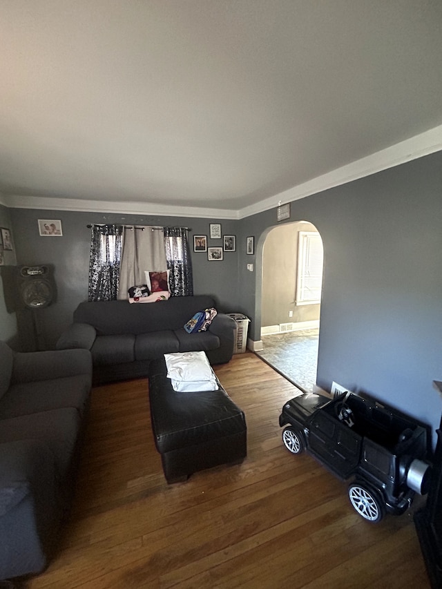 living room with crown molding, wood finished floors, and arched walkways