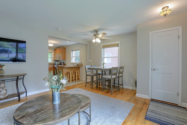living room with light wood finished floors, a ceiling fan, and baseboards