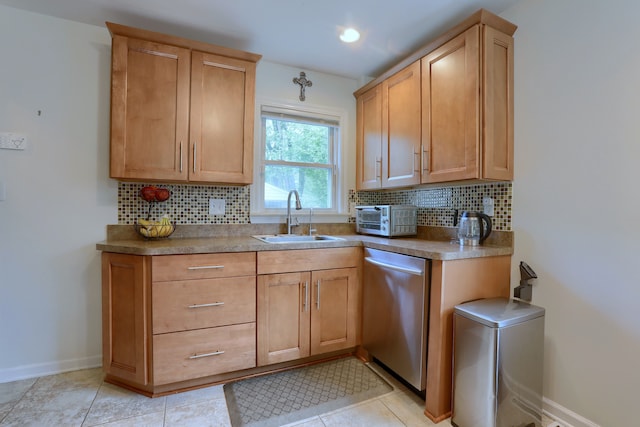 kitchen featuring a sink, dishwasher, decorative backsplash, and baseboards