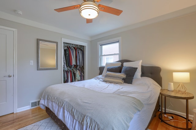 bedroom featuring a closet, wood finished floors, baseboards, and ceiling fan