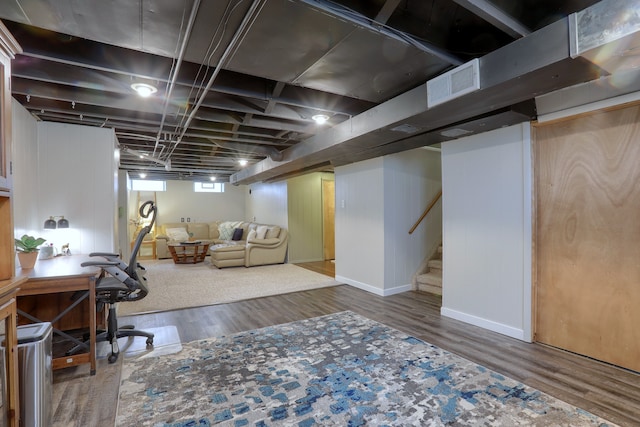 below grade area with wood finished floors, stairs, baseboards, and a desk