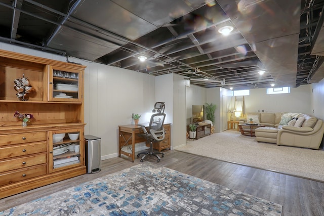 below grade area with wood finished floors, an office area, and baseboards