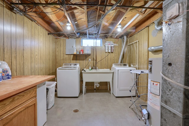 laundry area with independent washer and dryer, water heater, and wooden walls