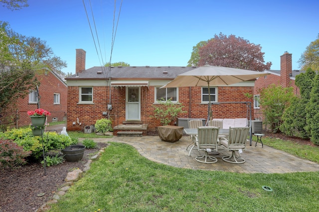 rear view of house with a chimney, brick siding, a patio area, and a yard