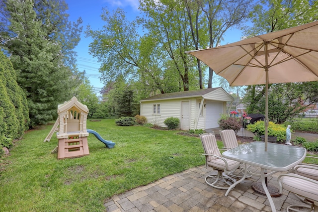 view of grassy yard with a playground, an outdoor structure, and a patio area