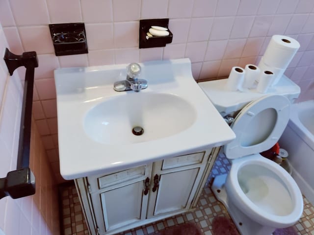 bathroom with toilet, vanity, and tile walls