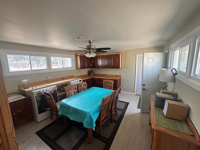 dining area featuring washer / clothes dryer, a ceiling fan, visible vents, and a wealth of natural light