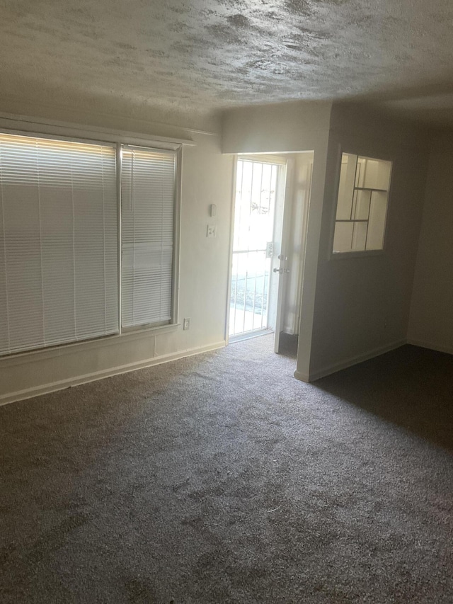 carpeted spare room featuring baseboards and a textured ceiling