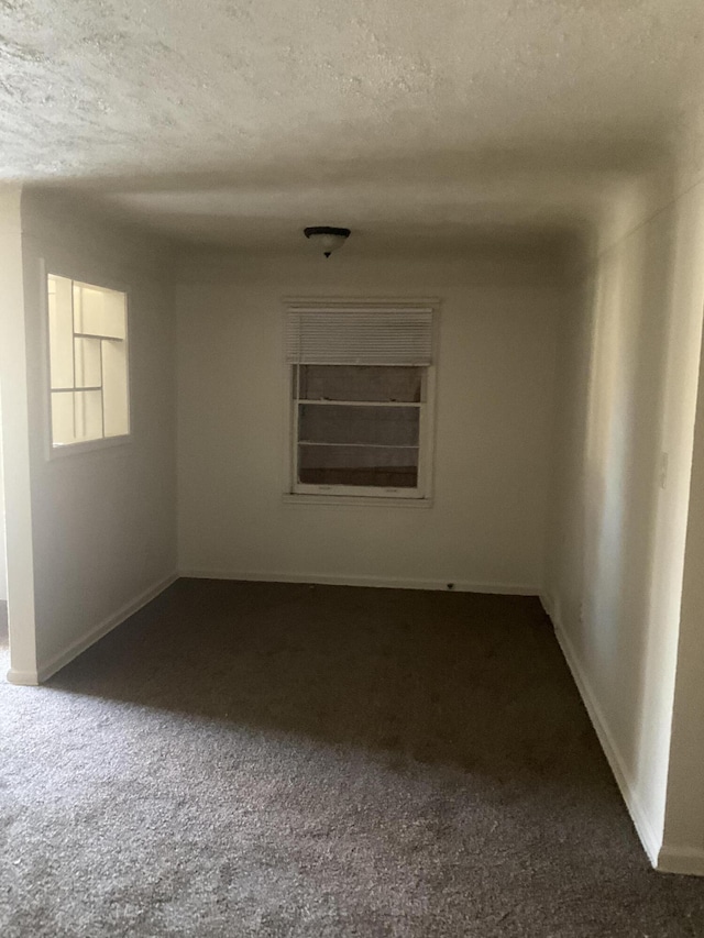 unfurnished room featuring a textured ceiling, baseboards, and dark colored carpet