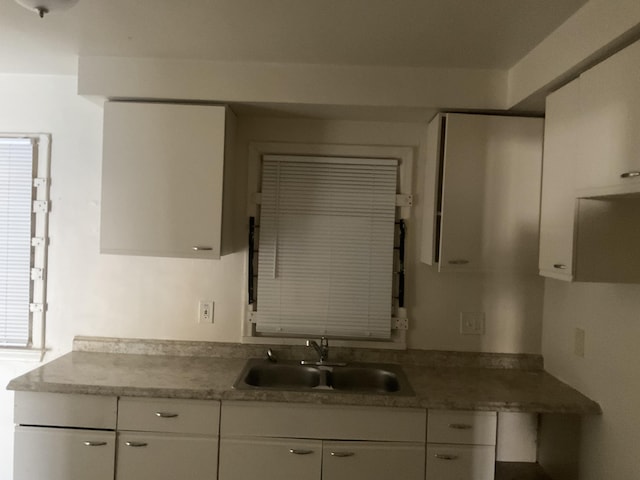 kitchen featuring a sink, white cabinets, and light countertops