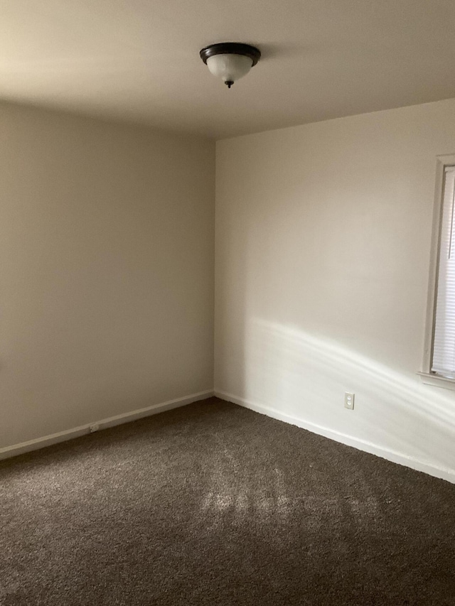 empty room featuring carpet and baseboards