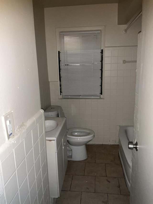 bathroom featuring tile walls, toilet, wainscoting, tile patterned floors, and vanity