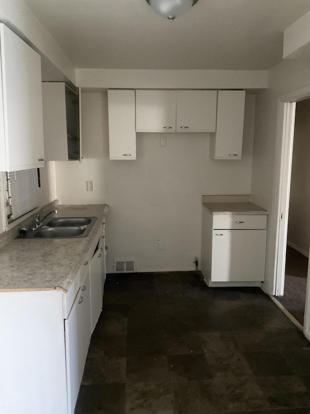 kitchen featuring visible vents, white cabinetry, light countertops, and a sink