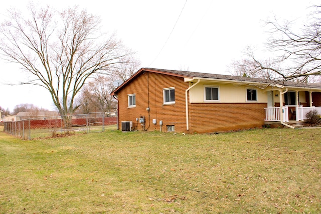rear view of house featuring a gate, fence, cooling unit, a yard, and brick siding