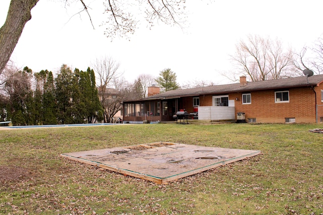 back of property featuring brick siding, a chimney, and a lawn