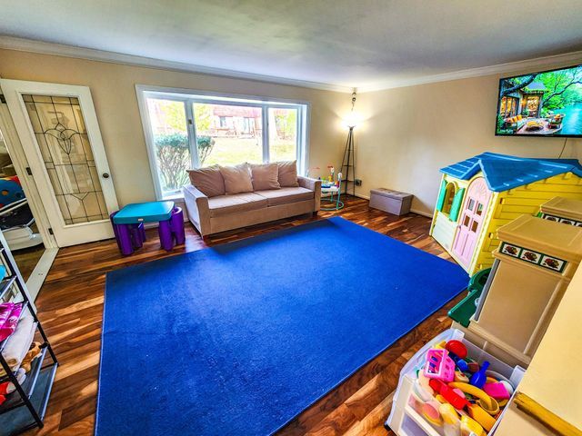 living area featuring ornamental molding and wood finished floors
