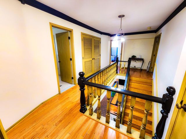 stairs featuring crown molding and wood finished floors