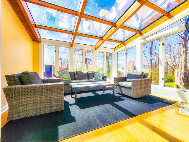 sunroom / solarium featuring a skylight, a wealth of natural light, wood finished floors, and coffered ceiling