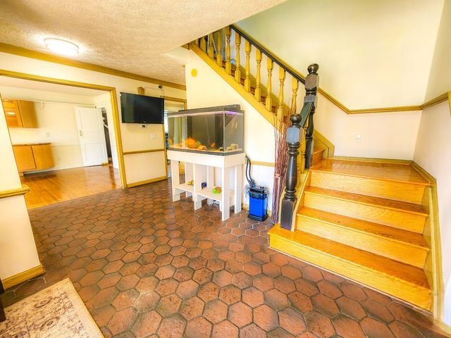 stairs with crown molding, a textured ceiling, and baseboards