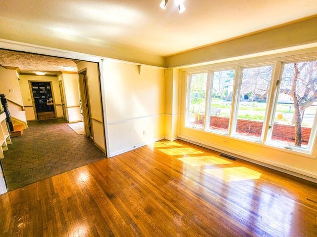 empty room with baseboards, wood finished floors, and visible vents