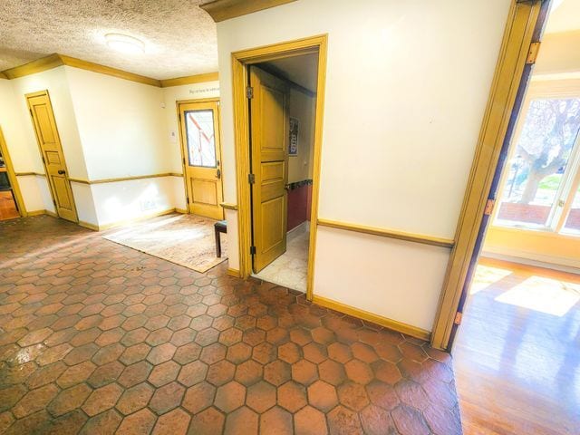 unfurnished room with baseboards, ornamental molding, and a textured ceiling