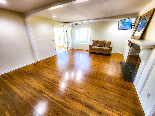 living area with arched walkways, baseboards, wood finished floors, and a fireplace