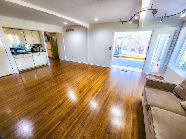living area with visible vents, baseboards, and wood finished floors
