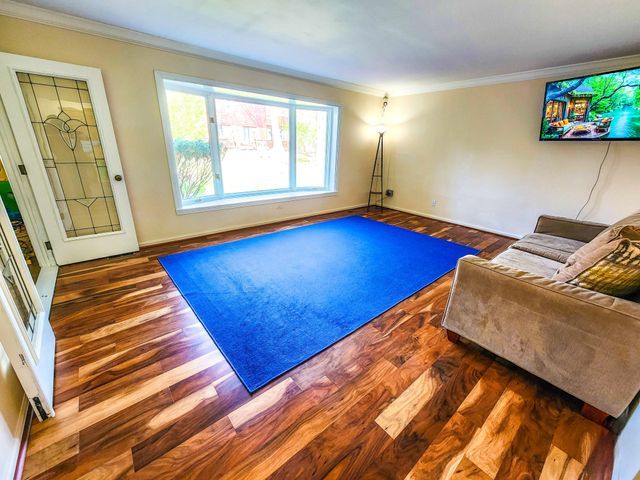 living area featuring baseboards, ornamental molding, and wood finished floors