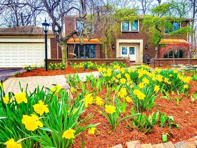 view of front of home with an attached garage, aphalt driveway, and brick siding