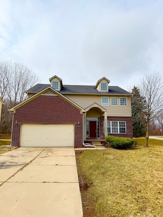 traditional-style home with brick siding, an attached garage, concrete driveway, and a front yard