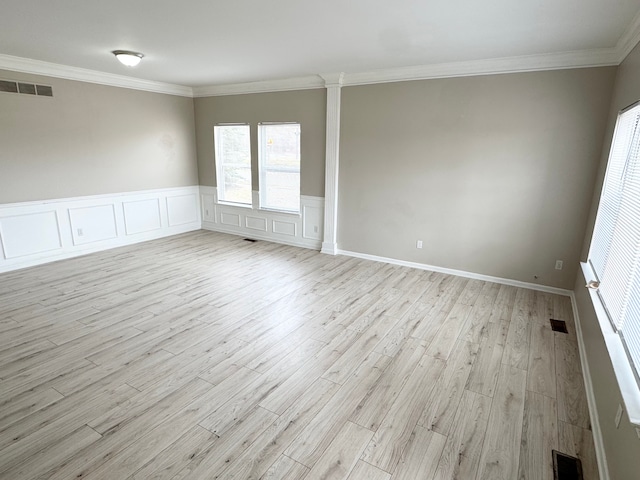 empty room featuring visible vents, light wood-style floors, and ornamental molding