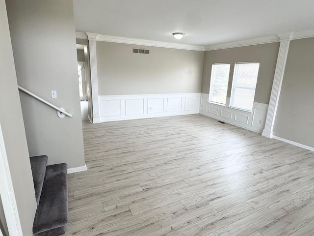 spare room featuring light wood-type flooring, visible vents, crown molding, decorative columns, and stairs