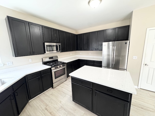 kitchen featuring dark cabinetry, light wood-style floors, appliances with stainless steel finishes, and a center island