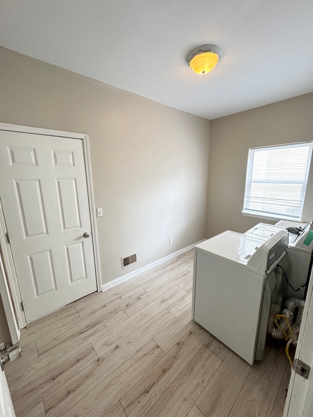 laundry area featuring visible vents, light wood-style floors, baseboards, laundry area, and washing machine and clothes dryer