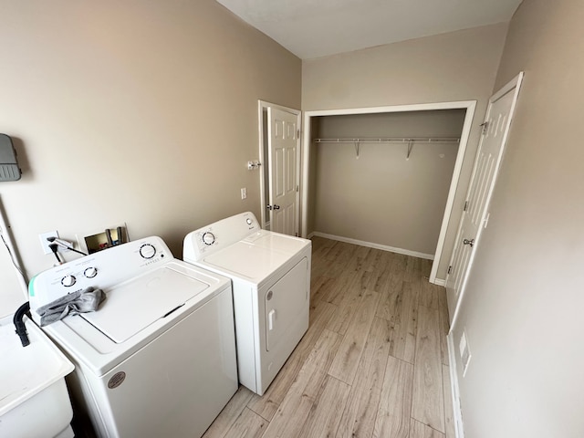 clothes washing area with washing machine and clothes dryer, baseboards, laundry area, light wood-style floors, and a sink