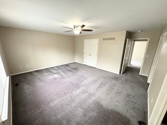 spare room with dark colored carpet, visible vents, baseboards, and ceiling fan