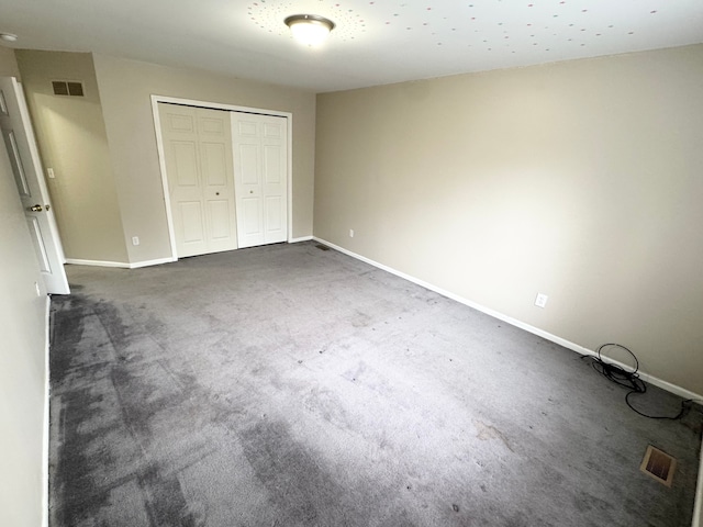 unfurnished bedroom featuring a closet, visible vents, baseboards, and dark colored carpet