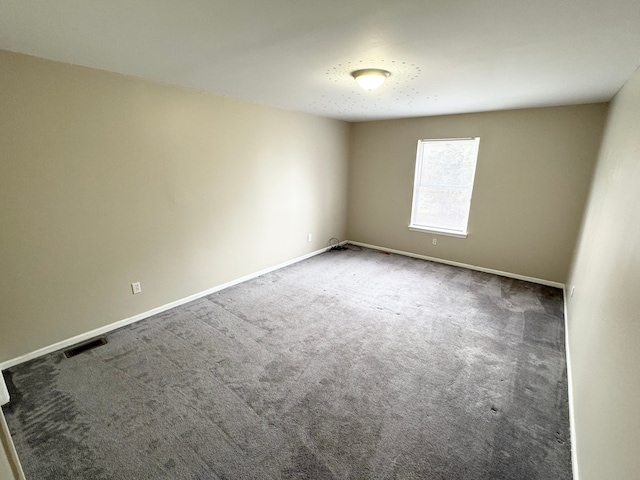 carpeted spare room with visible vents and baseboards