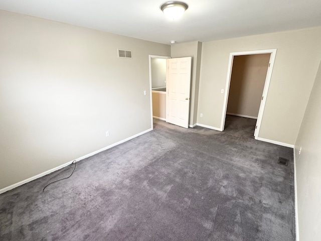 unfurnished bedroom with visible vents, dark carpet, and baseboards