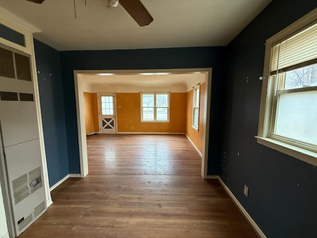 empty room featuring wood finished floors, baseboards, and ceiling fan