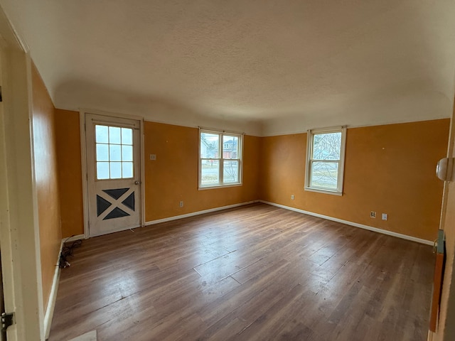 interior space with a textured ceiling, baseboards, and wood finished floors