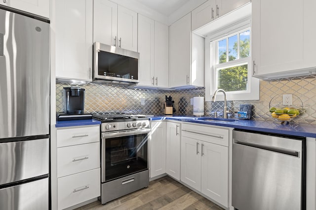 kitchen with a sink, dark countertops, white cabinets, and stainless steel appliances