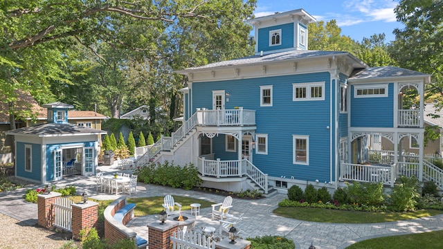 back of property featuring a patio, stairway, outdoor dining area, and an outdoor fire pit