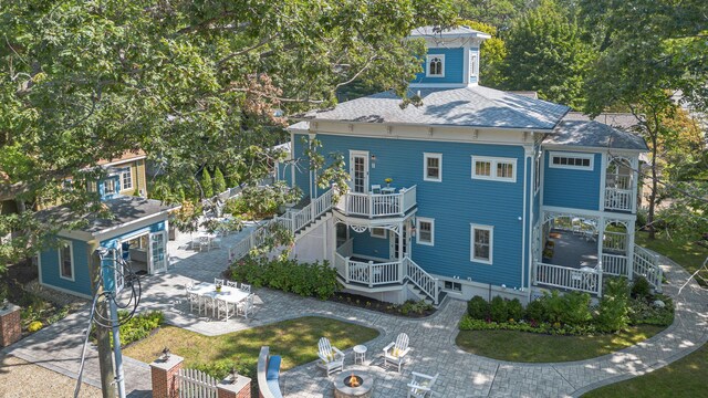 exterior space featuring a fire pit, stairs, roof with shingles, a yard, and a patio